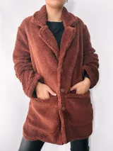 Saco largo color marrón chocolate, estilo teddy, con solapas y bolsillos laterales. Cierre frontal con botones. Talle único oversize.