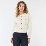 Sweater de punto color blanco con diseño de rombos en relieve y pequeños corazones rojos bordados. Presenta cuello redondo y puños acanalados.