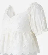 Blusa peplum color blanco, confeccionada en algodón, con escote corazón, mangas abullonadas cortas y bordado floral.