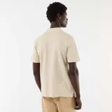 Remera polo de piqué color beige, de manga corta, con cuello camisero y cierre frontal de tres botones.