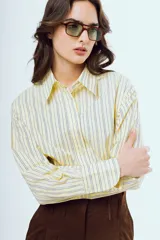 Camisa de manga larga con diseño a rayas verticales en tonos celestes y amarillos sobre fondo blanco, cuello camisero clásico y cierre frontal de botones.