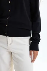 Saco de punto básico color negro, con cuello redondo y cierre frontal de botones dorados.