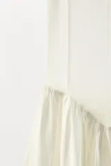 Vestido midi color blanco, de punto fino con cuello redondo y tirantes. Presenta una silueta ajustada en la parte superior y una falda asimétrica con volumen y frunces.