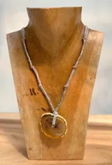 Collar con cordón gris, cuentas plateadas y dije de piedra natural color miel con borde dorado.