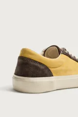Zapatilla de estilo retro fabricada en una combinación de piel con acabado serraje y algodón, en tonos marrón y amarillo, con suela contrastada.