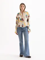 Camisa de seda color beige con estampado colorido de frutas, cuello camisero, mangas largas y ajuste elástico en la cintura.