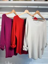 Sweater de tejido de punto fino en color blanco, con cuello en V y mangas largas. Presenta un diseño holgado y versátil, ideal para usar como prenda única o en capas.