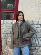 Blazer de lana en tono marrón con textura espigada, cuello con lazo integrado y bolsillos frontales de cuero en contraste.