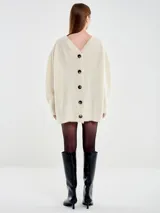 Cardigan de punto color blanco con silueta holgada y escote en V profundo. Presenta cierre frontal de cuatro botones oscuros, mangas largas y dos bolsillos tipo parche en la parte delantera. Confeccionado en una mezcla de alpaca, poliamida y lana.