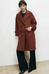 Abrigo de lana de corte recto y diseño cruzado con doble botonadura frontal. Presenta solapas clásicas, bolsillos laterales y mangas largas con detalle de botones en los puños.