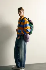 Mochila multibolsillos de diseño colorblock en tonos verde, azul marino, marrón y violeta, con solapa frontal y cierre de hebilla ajustable.