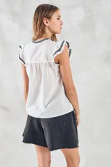 Blusa de color blanco con detalles bordados en negro, cuello redondo con cordones ajustables y mangas cortas con volados.