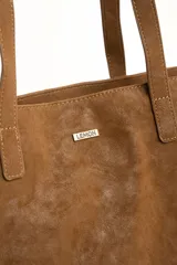 Bolso tipo tote bag de tamaño maxi color suela, confeccionado en material sintético con textura efecto cuero gastado. Cuenta con doble asa de hombro y placa metálica con la inscripción de la marca en la parte frontal.