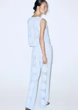 Pantalón tejido de punto celeste con diseño calado de flores, de corte recto y tiro medio con cintura elástica.