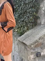 Vestido corto color marrón de tela gamuzada con mangas 3/4 y apliques de encaje negro en escote y mangas. Escote en V.