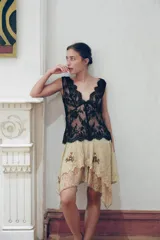 Falda corta de tiro bajo confeccionada en tul color beige, con capas, bajo asimétrico, bordados florales oscuros con lentejuelas en contraste y cierre lateral con nudo.