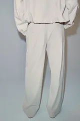 Pantalón de tiro medio color beige, de pierna ancha y corte recto. Cuenta con cintura elástica ajustable con cordones y bolsillos frontales.