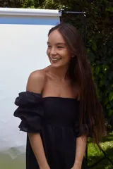 Vestido negro con escote recto, mangas largas abullonadas con elástico y largo a la rodilla.