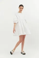 Vestido corto blanco de algodón con lurex, corte evasé, mangas cortas abullonadas y cuello redondo con ribete amarillo.