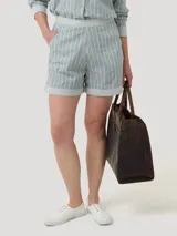 Short de tiro alto confeccionado en mezcla de lino y algodón orgánico. Presenta un diseño de rayas verticales en tonos gris y blanco, con bolsillos laterales y dobladillo vuelto en las piernas. Incluye cierre invisible lateral.