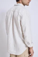 Camisa de corte regular con diseño de rayas verticales finas en tonos claros, cuello clásico y mangas largas con puños abotonados.