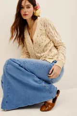 Cardigan de punto color beige con escote en V, cierre frontal con botones y detalles de flores bordadas en relieve a lo largo de la abertura. Cuenta con mangas largas y terminaciones en rib.