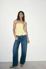 Top color amarillo claro, sin mangas y con escote recto. El bajo tiene un acabado peplum.