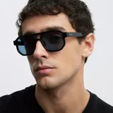 Lentes de sol estilo aviador con montura geométrica oversize en color negro y cristales polarizados en color azul. Presentan un diseño de doble puente con bordes biselados.