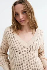 Sweater de tejido calado color beige, con escote en V y mangas largas holgadas con puños ajustados.