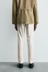 Pantalón chino de corte ajustado, color beige, con bolsillos laterales y bolsillos traseros de vivo. Cuenta con cierre frontal de cremallera y botón.