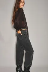 Jean de corte barrel, color negro, con diseño de pierna curva y holgada. Presenta cierre frontal con botón y bolsillos laterales.