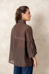 Camisa de organza blanca con cuello clásico, cierre frontal de botones y mangas tres cuartos abullonadas tipo globo con puños definidos.