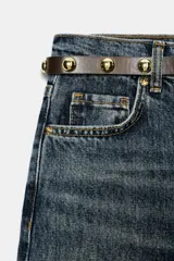 Jeans de tiro alto color azul claro, con cinco bolsillos y pernera recta que se estrecha hacia el tobillo. Incluye un cinturón negro con detalles metálicos. Cierre frontal con cremallera y botón.