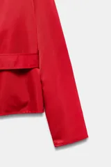 Cazadora corta de Zara color rojo, con cuello smoking, manga larga y cinturón ajustable del mismo tejido.