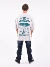 Remera de manga corta color gris claro, corte oversize, con cuello redondo y un pequeño estampado en el pecho con texto en color verde.