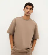 Remera masculina de corte oversize, color beige, con cuello redondo, manga corta y sisa desplazada. Confeccionada en tejido de algodón y poliéster, sin estampados.