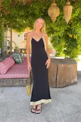 Vestido largo negro Lady Pipa con tirantes finos, escote en V y detalles en tejido dorado brillante en los laterales y el bajo.