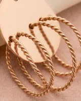 Caravanas colgantes de acero en tono rose gold, compuestas por un disco superior liso y una estructura inferior formada por múltiples aros entrelazados de textura trenzada.
