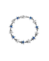 Pulsera de eslabones plateados con dijes de estrellas en relieve, con centro esmaltado en color azul vibrante. Cuenta con un cierre de mosquetón.