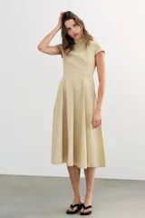 Vestido midi de gabardina en color beige, con cuello subido, manga corta y falda acampanada con caída fluida.