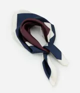 Pañuelo cuadrado de tejido satinado con estampado geométrico en tonos azul marino, bordó y blanco. Presenta una caída fluida y versátil para usar en el cuello, cabello o como accesorio.