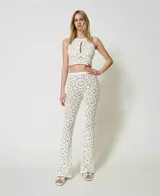 Pantalón acampanado de algodón tejido a crochet con estampado floral, bordes festoneados, cintura elástica y forro corto en contraste.