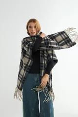 Ruana de tejido suave con diseño de cuadros grandes en tonos azul marino y beige, terminada con flecos en los extremos.