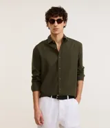 Camisa de algodón color verde militar, con cuello inglés, manga larga, cierre frontal con botones y textura maquinetada.
