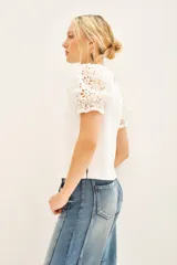 Remera blanca de algodón con calce al cuerpo, cuello redondo y tajos laterales. Mangas balloon con detalle de broderie.