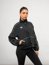 Campera deportiva Umbro de nylon color negro, con cuello alto, cierre frontal y detalles de líneas blancas en contraste. Presenta bolsillos laterales y puños elásticos.