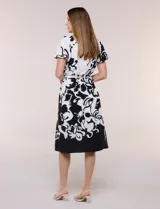 Vestido midi de calce fluido con escote redondo y mangas cortas abullonadas con terminación elástica. Presenta un fino cinturón a tono para ajustar la cintura y una falda evasé con estampa floral abstracta en blanco y negro.