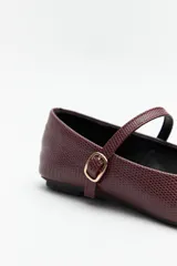 Balerinas color crudo de símil cuero texturizado, con punta redondeada, tira sobre el empeine y hebilla metálica ajustable.