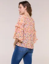 Blusa holgada de gasa estampada en tonos de amarillo, naranja y fucsia con diseño floral. Presenta escote redondo fruncido y mangas tres cuartos acampanadas con volados.