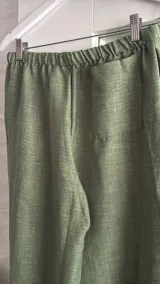 Pantalón ancho de tiro bajo, color verde claro, con cordón ajustable en la cintura y tiras laterales ajustables.